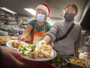 Volunteers, Michele Fera, left, and Eileen Dancel, serve up a Christmas dinner at the Downtown Mission on Christmas Day, on Saturday, Dec. 25, 2021.