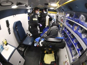 Essex-Windsor EMS paramedics Katie Rawlings and Mike Sherwood care for a man in the back of an ambulance on Saturday, November 13, 2021.