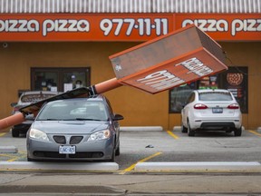 A large commercial sign toppled onto a parked car on Tecumseh Road East in Windsor during a windstorm Saturday, Dec. 12, 2021.