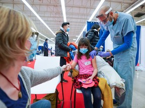 Kate Rhodes holds her mom's, Emma Rhodes, hand as she gets her shot at a Humber River Hospital vaccination clinic after Canada approved Pfizer's coronavirus disease (COVID-19) vaccine for children aged 5 to 11, in Toronto, Ontario, Canada November 25, 2021.