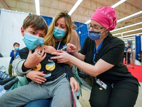 Dean Eliaz is comforted by his mom Michelle Eliaz as he gets his shot at a Humber River Hospital vaccination clinic after Canada approved Pfizer's coronavirus disease (COVID-19) vaccine for children aged 5 to 11, in Toronto, Ontario, Canada November 25, 2021.