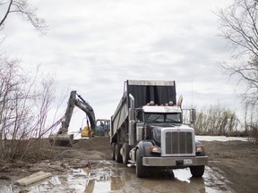 An excavator pushes around sand delivered by a dump truck at Hillman Marsh Beach, Wednesday, May 8, 2019. High lake levels have eroded much of the beach.