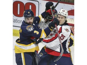 Erie Otters' defenceman Ryan Thompson, left, and Windsor Spitfires' forward Kyle McDonald battle in front of net on Thursday at the WFCU Centre.