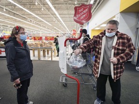 Salvation Army volunteer Connie Poisson watches Brent MacLachlan make a donation in a Christmas Kettle at the Walmart location on Dougall Avenue in Windsor on Dec. 21, 2021.