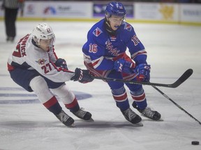 Windsor Spitfires' defenceman Michael Renwick, at left, battle Kitchener Rangers  Carson Rehkopf for the puck.