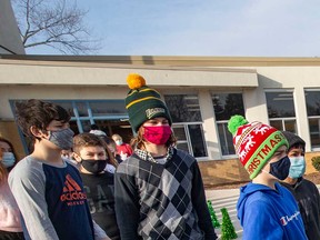 Students wearing masks stand outside St. Andre French Immersion Catholic Elementary School in Windsor on Dec. 10, 2021.