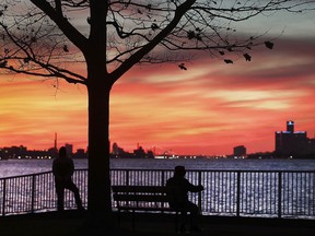 Two men watch the sunset along the Detroit River in Windsor on Monday, December 13, 2021.