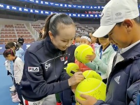 Chinese tennis player Peng Shuai signs large-sized tennis balls at the opening ceremony of Fila Kids Junior Tennis Challenger Final in Beijing, China, Nov. 21, 2021, in this screen grab obtained from a social media video.