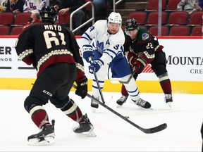 Toronto Maple Leafs centre Auston Matthews (34) passes the puck between Arizona Coyotes left wing Johan Larsson (22) and Dysin Mayo (61) during the first period at Gila River Arena on Wednesday.
