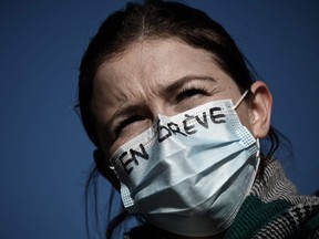 A health worker wearing a mask reading "on strike" takes part in a demonstration in Bordeaux, southwestern France on Jan. 11, 2022, to protest against working conditions and the level of financial means for hospitals in France.