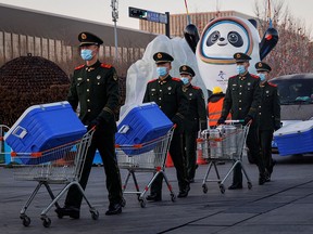 Paramilitary police officers walk past the mascot of the Beijing 2022 Winter Olympics in Beijing, China, January 15, 2022.