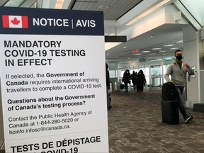 Travellers walk past a "Mandatory COVID-19 Testing" sign at Pearson International Airport during the COVID-19 pandemic of Toronto, Dec. 18, 2021.
