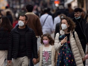 People wearing face masks walk down a street in Nantes, France, Friday, Dec. 31, 2021.