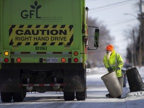 A worker with GFL Environmental picks up garbage on Scofield Avenue on Tuesday, January 4, 2021.