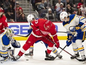 Detroit Red Wings left wing Adam Erne fights for possession of the puck against St. Louis Blues defenseman Jacob Bryson and goalie Aaron Dell during the second period at Little Caesars Arena.