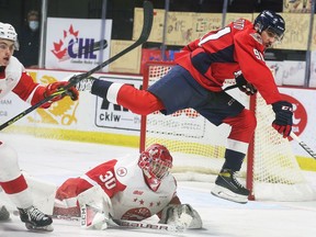 Windsor Spitfires' forward Pasquale Zito jumps over Sault Ste. Marie Greyhounds' goalie Tucker Tynan as defemce,am Caeden Carlisle moves in during Thursday's game.