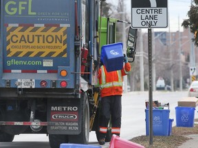 A Green For Life employee collects recycling materials along Lauzon Road in Windsor on Friday, January 14, 2022.