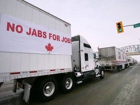 A truck adorned with a No Jabs for Jobs banner participates in a protest against vaccine mandates on Huron Church Road near the Ambassador Bridge on Sunday, Jan. 23, 2022.