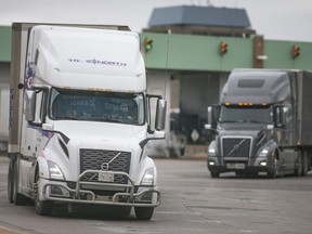 Transport trucks enter Canada after passing through Canadian customs at the Ambassador Bridge, on Friday, January 14, 2022.