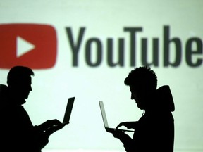 Silhouettes of mobile device users are seen next to a screen projection of a YouTube logo in this picture illustration taken March 28, 2018.