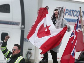 Anti-mandate protestors wave Canadian flags and placards on Huron Church Road southbound on Monday, Feb. 7, 2022.