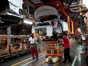 General Motors assembly workers connect a battery pack underneath a partially assembled 2018 Chevrolet Bolt EV vehicle on the assembly line at Orion Assembly in Lake Orion, Michigan, U.S.,