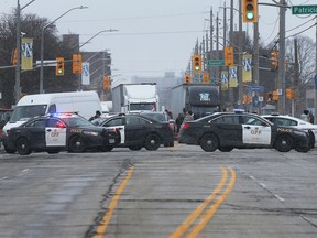 Windsor and Ontario Provincial officers are shown on Wyandotte Street West near the Ambassador Bridge entrance to the United States. Protestors have blocked access and there is no traffic on the bridge.