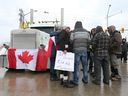 Demonstranten in der Nähe der Ambassador Bridge in Windsor hören sich am Freitag, den 11. Februar 2022, einen Livestream der morgendlichen Pressekonferenz des Premierministers von Ontario, Doug Ford, an.