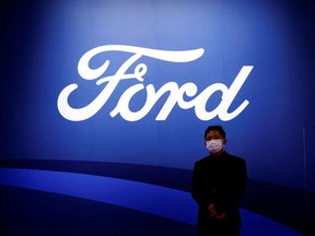 A man stands near the Ford logo during a media day for the Auto Shanghai show in Shanghai, China April 19, 2021.