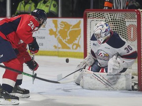Windsor Spitfires' forward Avval Baisov, at left, is  stopped by Saginaw Spirit goalie Tristan Lennox during a game earlier this season.
