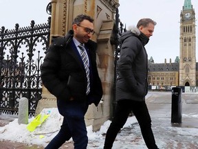 Canadian Minister of Transport Omar Alghabra (left) House of Commons leader Mark Holland walk past Parliament Hill in Ottawa on Feb. 21, 2022.