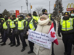 Protesters yell at police as they attempt to clear the anti-mandate blockade of the Ambassador Bridge on Huron Church Road on Saturday, Feb. 12, 2022.