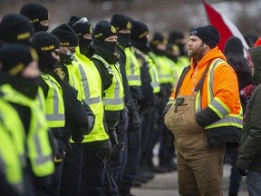 Protesters confront police as they attempt to clear the anti-mandate blockade of the Ambassador Bridge on Huron Church Road on Saturday, Feb. 12, 2022.