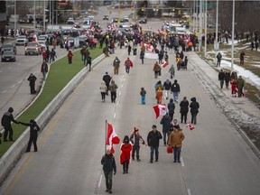 Demonstranten, die größtenteils nicht Teil der ursprünglichen Blockade sind, mischen sich am späten Nachmittag frei auf der Huron Church Road, nachdem die Polizei am Samstag, den 12. Februar 2022, einen Teil der Blockade der Ambassador Bridge geräumt hat.