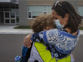 In this Sept. 7, 2021, file photo, parent Randa Kumail hugs her 12-year-old son, Anas Shebli, a Grade 7 student at Legacy Oak Trail Public School, after the first day of school ended.