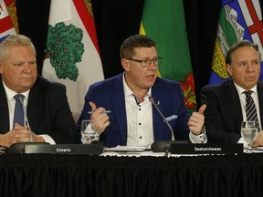 Saskatchewan Premier Scott Moe, centre, speaks flanked by Ontario Premier Doug Ford, left, and Quebec Premier Francois Legault at the Council of the Federation meetings in Toronto on December 2, 2019.