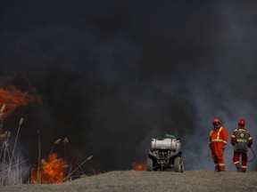 Dan Lebedyk, a biologist/ecologist at the Essex Region Conservation Authority, and Lloyd Holbrook, left, from Wildfires Specialist Inc., monitor a prescribed burn of approximately 17 hectares of Phragmites within the Callavino Wetland near the mouth of the River Canard, on Thursday, March 17, 2022.