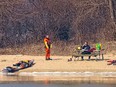 A U.S. Coast Guard helicopter crew member waits while a woman kayaker speaks on her phone on Peche Island on Wednesday, March 17, 2022.