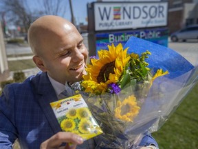 Edy Haddad, founder of Shine Bright YQG, is pictured with a bouquet of sunflowers and a package of sunflower seeds, outside the Budimir branch of the Windsor Public Library, on Tuesday, March 29, 2022.  Seeds are being given out as an act of solidarity with Ukraine.