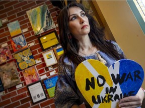 Anna Buckie holds a piece of her artwork inspired on the war in Ukraine, at Cafe Amor, on Friday, March 18, 2022.