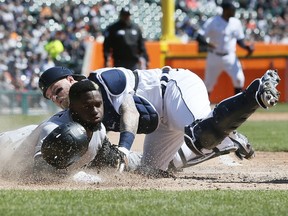 Catcher Tucker Barnhart of the Detroit Tigers tumbles over Luis Robert of the Chicago White Sox, who scored from first base on a double by Jose Abreu, during the third inning at Comerica Park on April 10, 2022, in Detroit, Michigan.