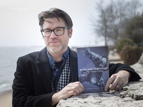 First-time author, Christopher Menard, is pictured with his book, At the End, Beginnings: A Memoir in Poems, on the shores of Lake Erie in Kingsville, on Tuesday, April 5, 2022.