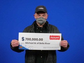 Michael Marshall of Belle River holds the $700,000 prize cheque he won from playing the Instant game Supreme 7.