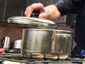 A fire prevention officer in Regina demonstrates how to cover a fire in a pot on a stovetop in this 2018 file photo.