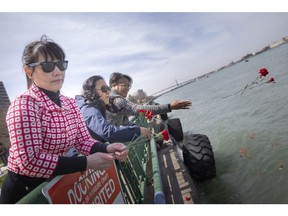 From left, Windsor District Labour Council members, Leilani Logronio, Elizabeth Ha, and Rush Glenn, throw flowers into the Detroit River to commemorate the National Day of Mourning, on Thursday, April 28, 2022.