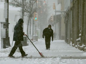 A person clears snow from the front of a business during a storm in Winnipeg on Wednesday, April 13. Just when we thought we were done with our shovels … bam … winter returns with fury. Chris Procaylo/Winnipeg Sun