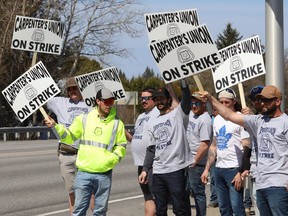 Members of the Carpenters Union local 2486 picket in Azilda, Ont. while taking part in a provincewide strike on Monday.