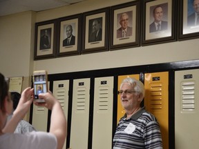 David Cozens poses for a picture with a photo of his father, Reg Cozens, above him on the wall at General Amherst High School on Saturday, May 14, 2022. Reg Cozens was the school's principal from 1962 to 1969, and David graduated in 1969 .