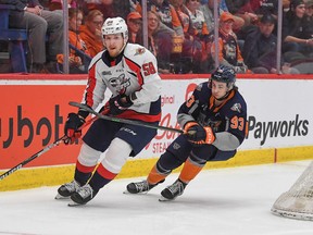 Windsor Spitfires' defenceman Andrew Perrott, who scored the game-winning goal in overtime, tries to pull away from Flint Firebirds' forward Amadeus Lombardi.