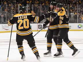 Bruins defenceman Derek Forbort (28) celebrates with left wing Tomas Nosek (92) and centre Curtis Lazar (20) after scoring a goal against the Hurricanes during the third period at the TD Garden in Boston, Thursday, May 12, 2022.